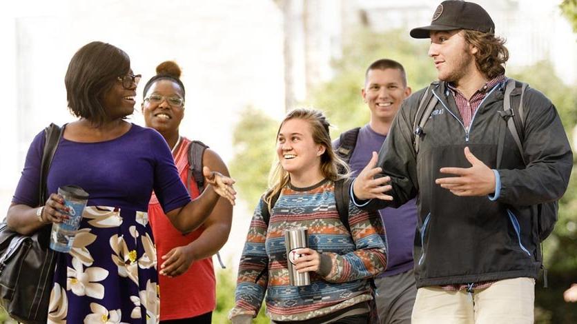 Professor talking and walking with group of students between classes